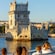 A group of people looking at Belém Tower, a structure surrounded by water